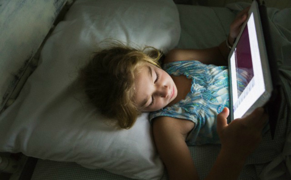 Bambina con tablet letto